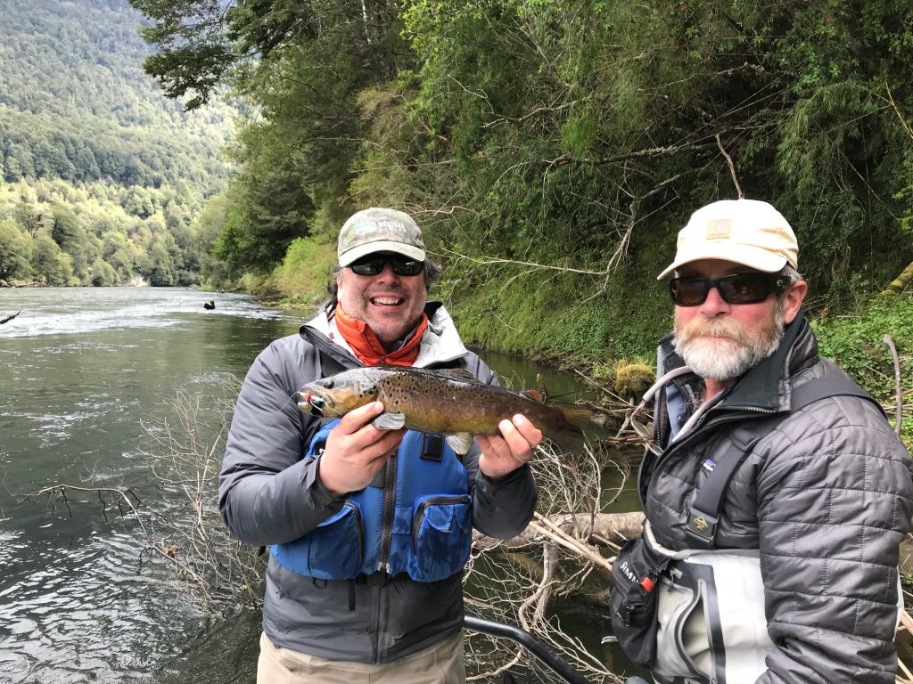 Guide Monte Becker and an angler holding a brown trout in the river