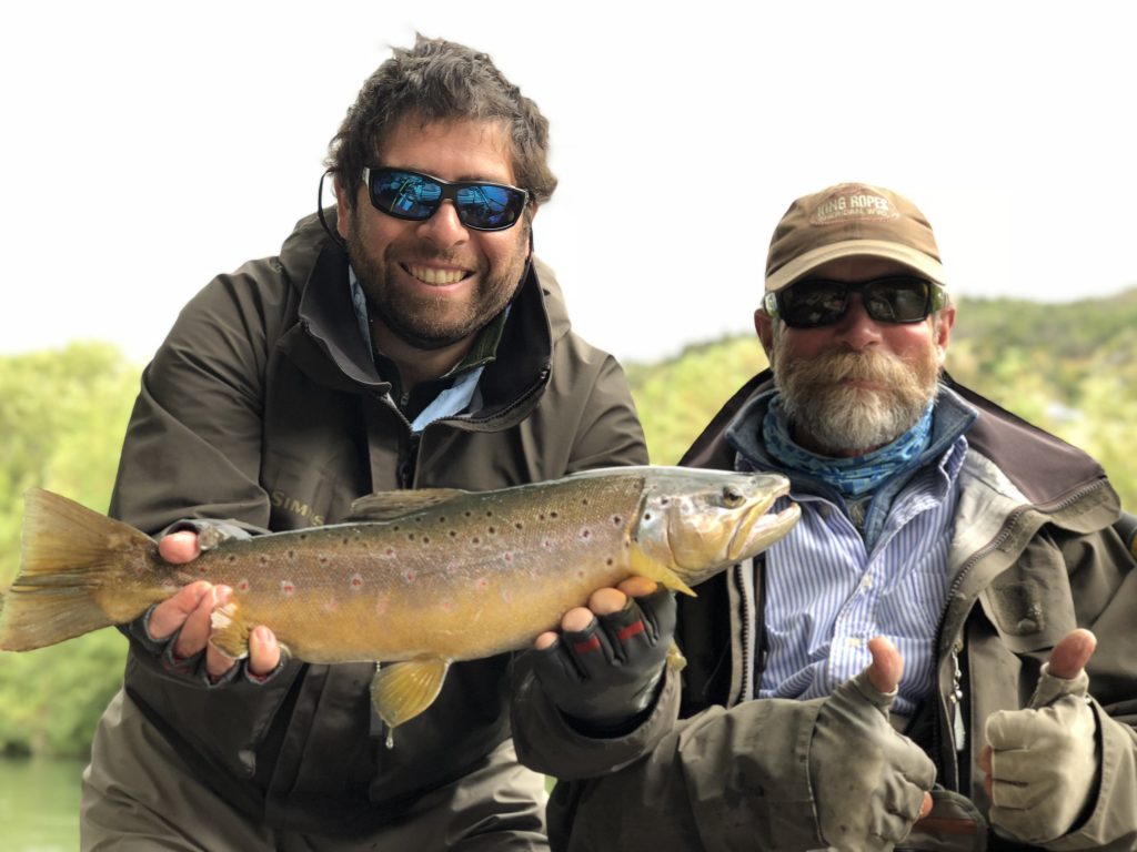 Guide Monte Becker and a client showing a brown trout by the river