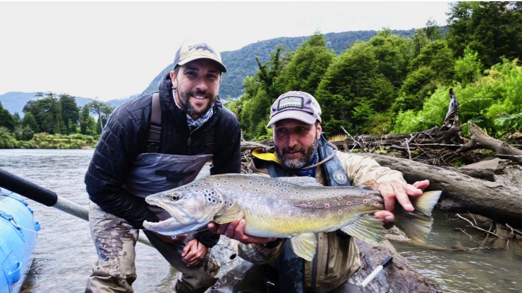 Two anglers holding a large brown trout on the Río Blanco